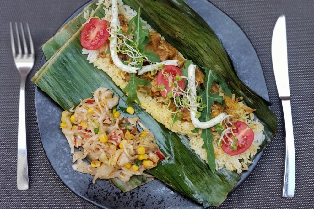 Na talerzu tempeh z duszonym po tajsku porem, grillowany w liściu bananowca podawany z ryżem